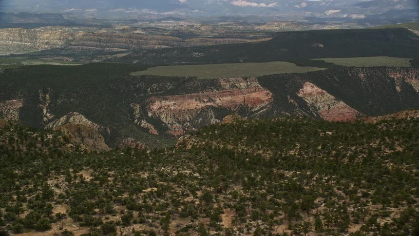Aerial footage soaring over a mountain ridge unveiling a desert road in the breathtaking landscape of Grand Staircase-Escalante National Monument Utah on a partly cloudy day