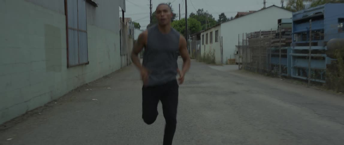 A man running on a side street near a building on a cloudy day