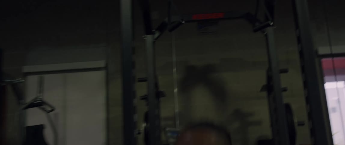 Close up of a man working out on a lift bar indoors before getting off and jumping around aggressively