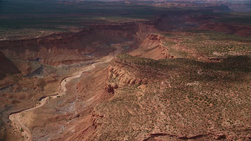 A stunning aerial view of a dry riverbed in a desert canyon located in the Navajo Nation Reservation on the border of Arizona and Utah featuring breathtaking Southwest United States landscape during a partly cloudy summer day