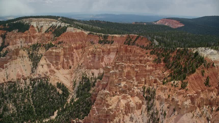  aerial footage captures the breathtaking approach to the famous pink cliffs and hoodoos of Bryce Canyon National Park in Utah showcasing the stunning rock formations and striations with partly cloudy skies adding to the scenic beauty