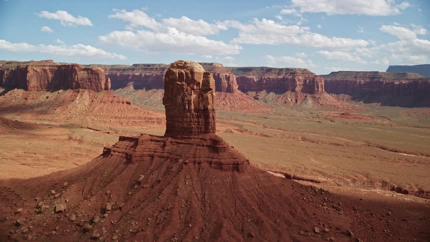 Aerial footage captures the stunning red rock formation on a partly cloudy day in the desert valley of Navajo Nation Reservation Arizona Utah
