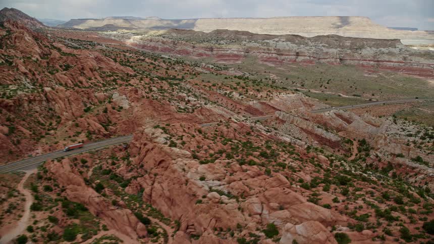 Aerial footage pans across Highway 89 showcasing vehicles traversing through canyons and mountains in the scenic Glen Canyon National Recreation Area during a sunny summer day in Utah and Arizona
