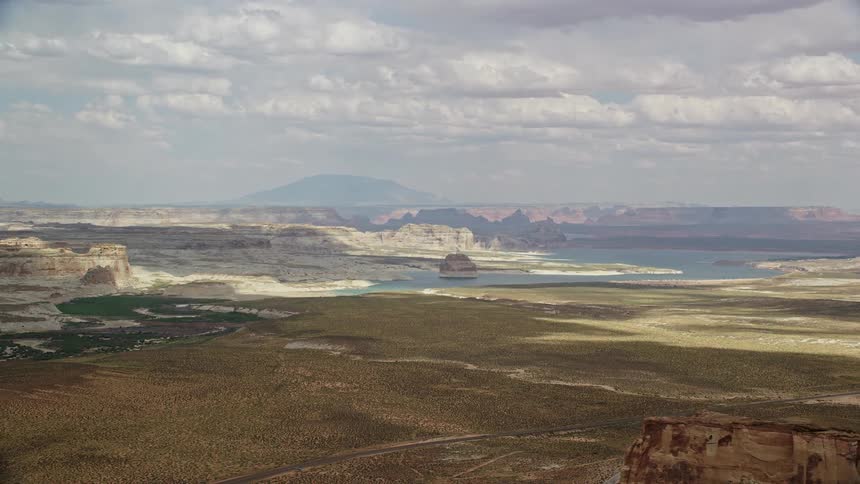  aerial footage captures the stunning landscape of Lone Rock and Lake Powell surrounded by the beauty of Glen Canyon National Recreation Area in Utah and Arizona showcasing the arid desert landscape and the tranquil waters of the reservoirs
