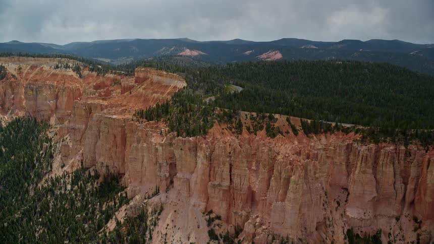 Aerial footage of passing by rock formations and treelined red rock cliff in Bryce Canyon National Park Utah during summer