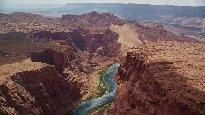 A stunning aerial view of the Colorado River flowing through the majestic cliffs of Glen Canyon in Arizona showcasing the natural beauty of the Southwest United States during a sunny summer day