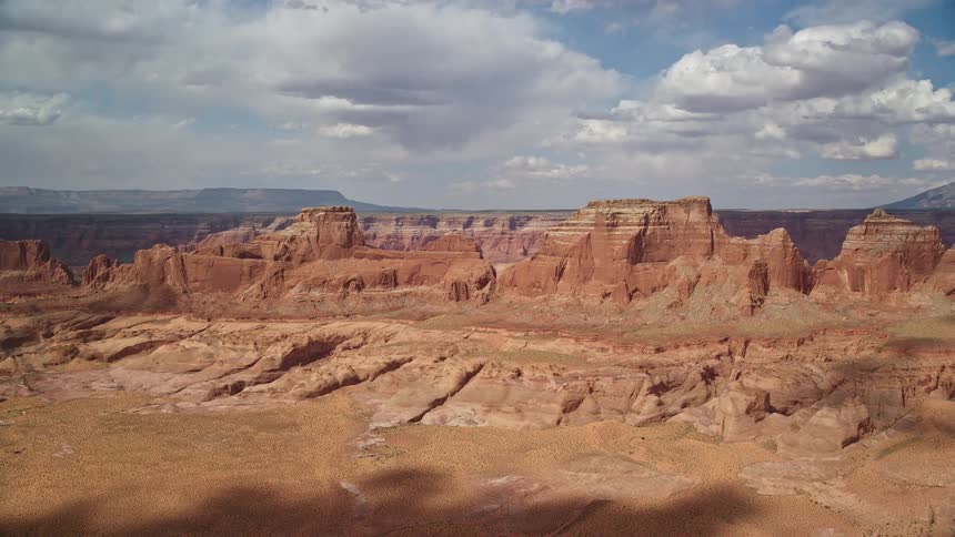 Approaching row of buttes on Navajo Nation Reservation Arizona captured in stunningaerial footage during a partly cloudy day in the arid desert landscape showcasing the majestic natural beauty of the Southwest United States