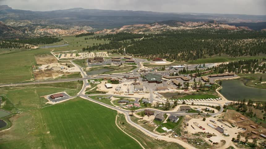 Aerial view of a small town and hotels near fields a pond and forest in Bryce Utah during summer