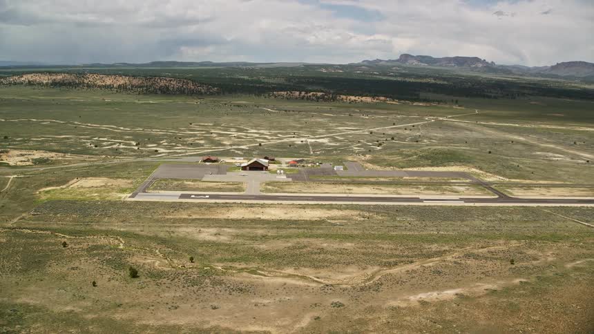 Aerial view of Bryce Canyon Airport in Utah with a single runway wood hangar and small airfield during a partly cloudy summer day