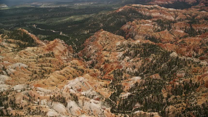 Fly over the scenic hills trees and dirt road winding through the breathtaking canyon at Bryce Canyon National Park in Utah during a beautiful sunny day in the summertime