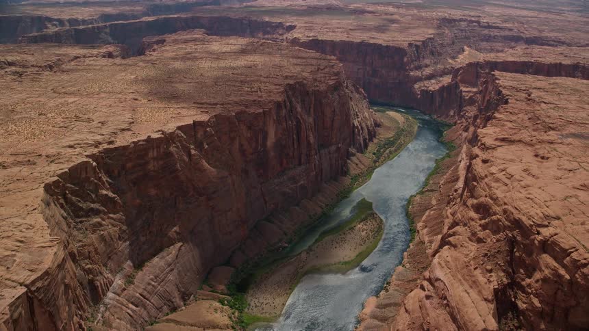 Aerial footage showcasing the breathtaking beauty of the Colorado River and Glen Canyon in Arizona as the camera flies towards them and pans across capturing the arid desert landscape and natural river flowing through the majestic canyon