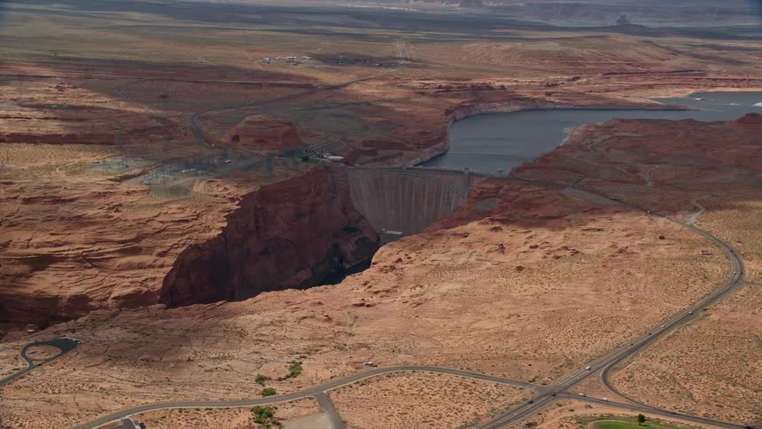 Aerial footage of traffic running on roads near the Glen Canyon Dam and Bridge in Arizona during the summer
