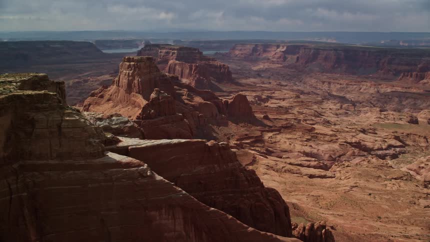 Aerial footage of flying by a row of large red rock buttes on the Navajo Nation Reservation in Arizona during a cloudy day