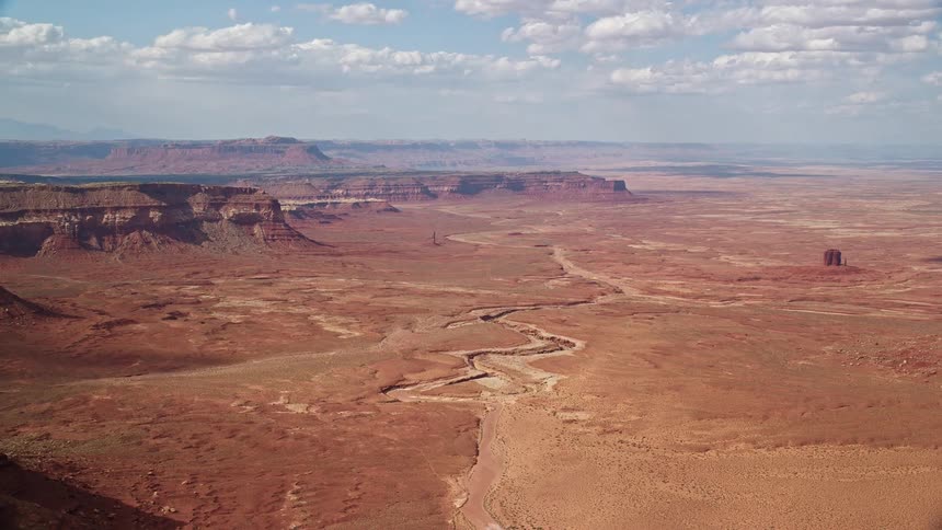 Aerial footage of a wild desert landscape with rocky mountains and buttes in the Navajo Nation Reservation Arizona and Utah captured during daytime in the Southwest United States