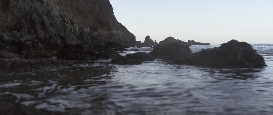 Water splashes against the rocks on a cloudy day