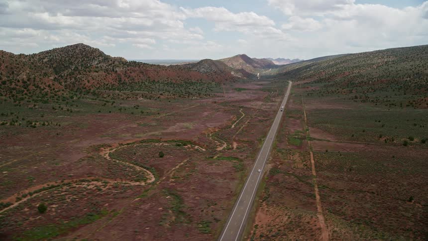 Aerial footage of a bright sunny day flying over Highway 89 in Glen Canyon National Recreation Area capturing light traffic and the surrounding desert landscape of Utah and Arizona