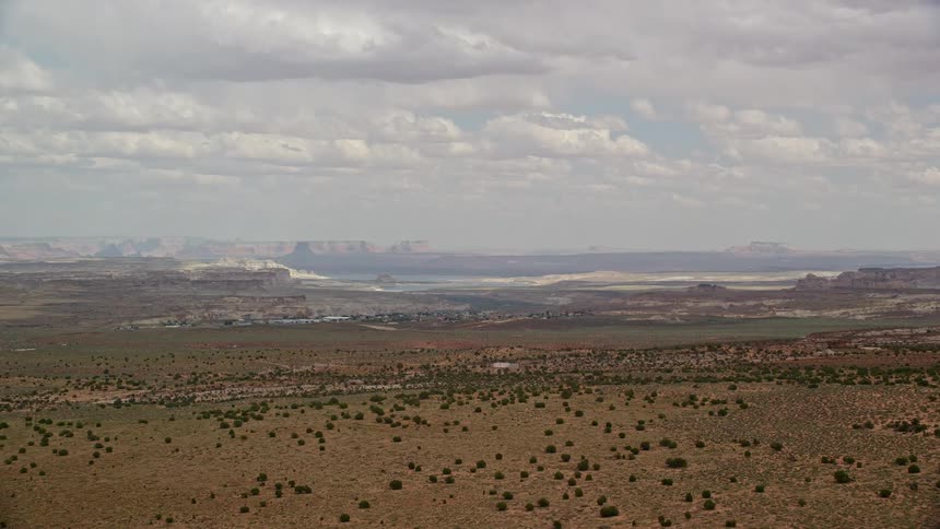 Aerial footage showcasing the majestic buttes and open desert with a small town and rural residential areas coming into view in Big Water Utah during summertime