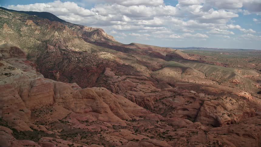  aerial footage of approaching rock formations mountain peak and slopes in Navajo Mountain Utah showcasing the natural beauty of the arid landscape during the day with partly cloudy skies