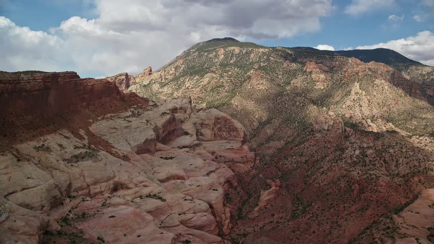  aerial footage showcasing the majestic Navajo Mountain in Utah with breathtaking mountain peaks desert landscapes and partly cloudy skies as seen from a side view perspective