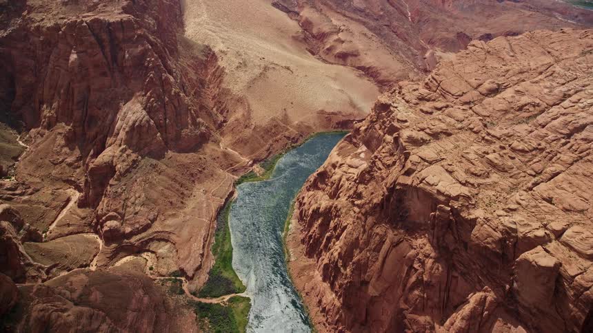 an bird's eye view of the Colorado River winding through the majestic cliffs of Glen Canyon Arizona captured during a sunny day in the Southwest United States