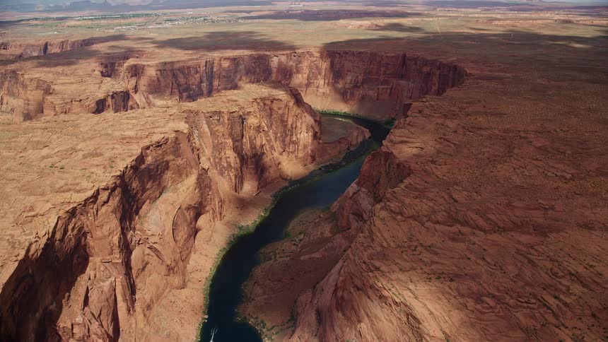  aerial footage of flying over Colorado River approaching Horseshoe Bend in Glen Canyon Arizona with cloud shadows rolling over the river in a desert canyon landscape during the day in Utah