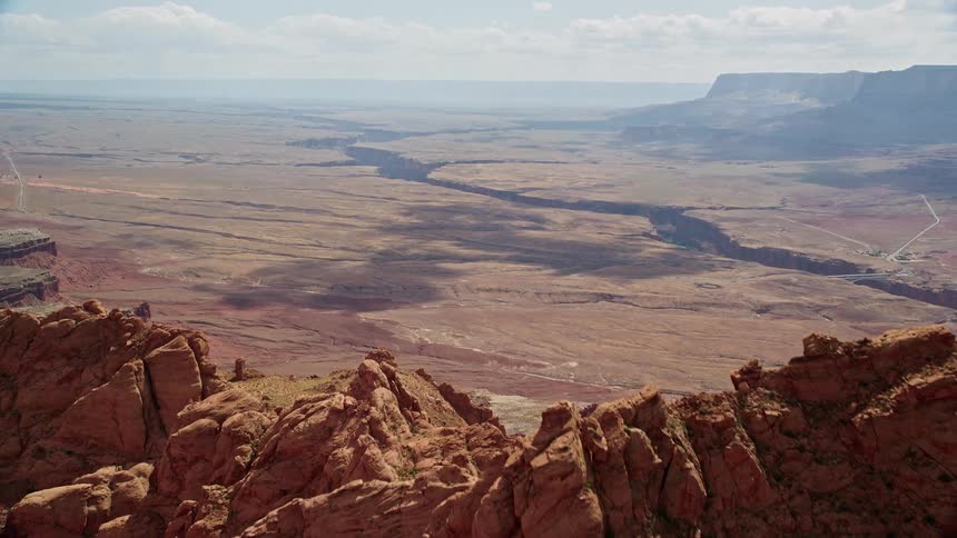 Aerial footage showcases the stunning Marble Canyon at Glen Canyon National Recreation Area as the drone flies over rocky peaks and reveals the vast and beautiful landscape of Utah and Arizona during a sunny summer day