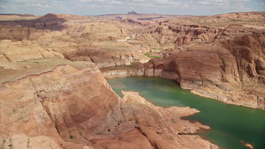  aerial footage showcasing the scenic beauty of Navajo Canyon's canyon cliffs Lake Powell rivers and coves amidst an arid southwest desert landscape captured during a sunny day in Utah's summer season