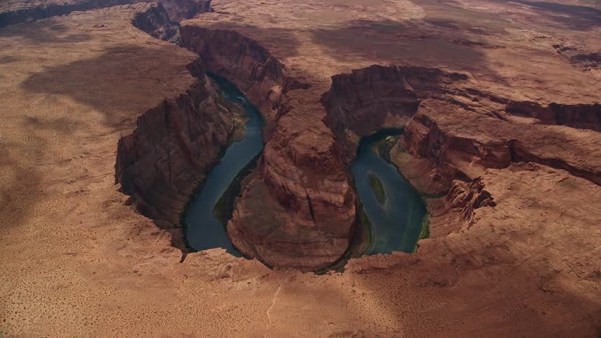 Aerial footage of flying to the edge of Horseshoe Bend with a tilt down to the Colorado River in Glen Canyon Arizona showcasing the natural beauty of this arid gorge in the Southwest United States during a partly cloudy summer day