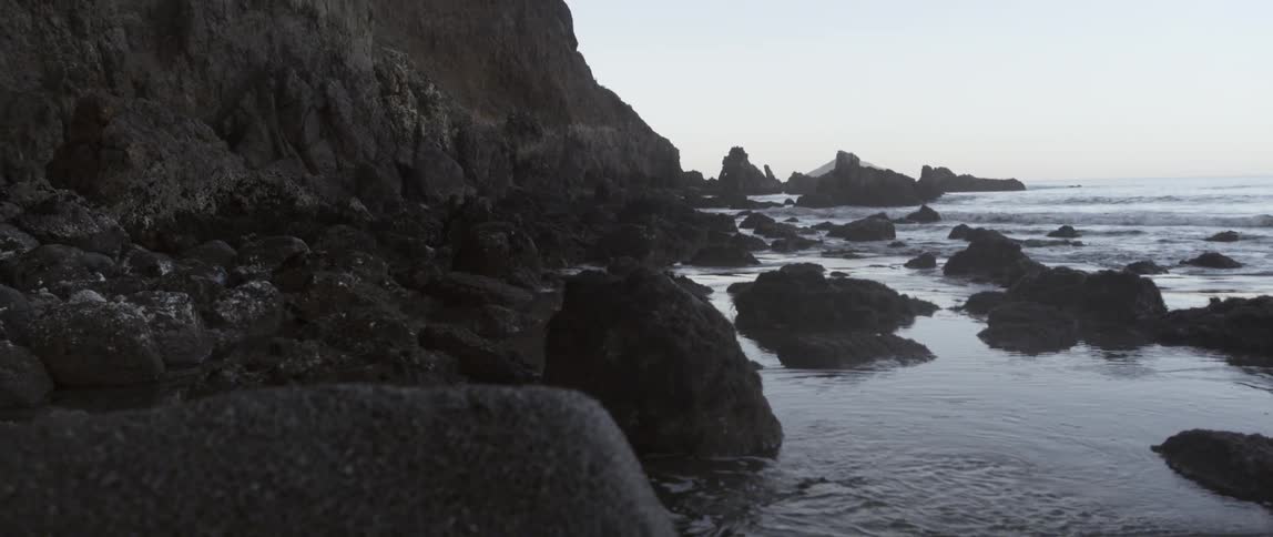 The shore is lined with rocks and a cliff