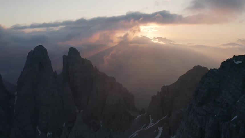 An aerial view of snow covered mountains is displayed at dusk