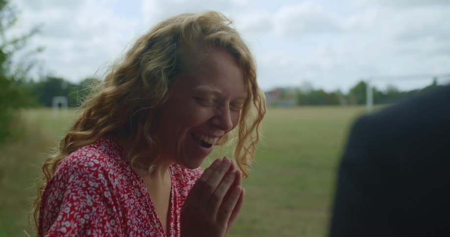 A woman is surprised as a man sitting opposite her gives her something (ring)