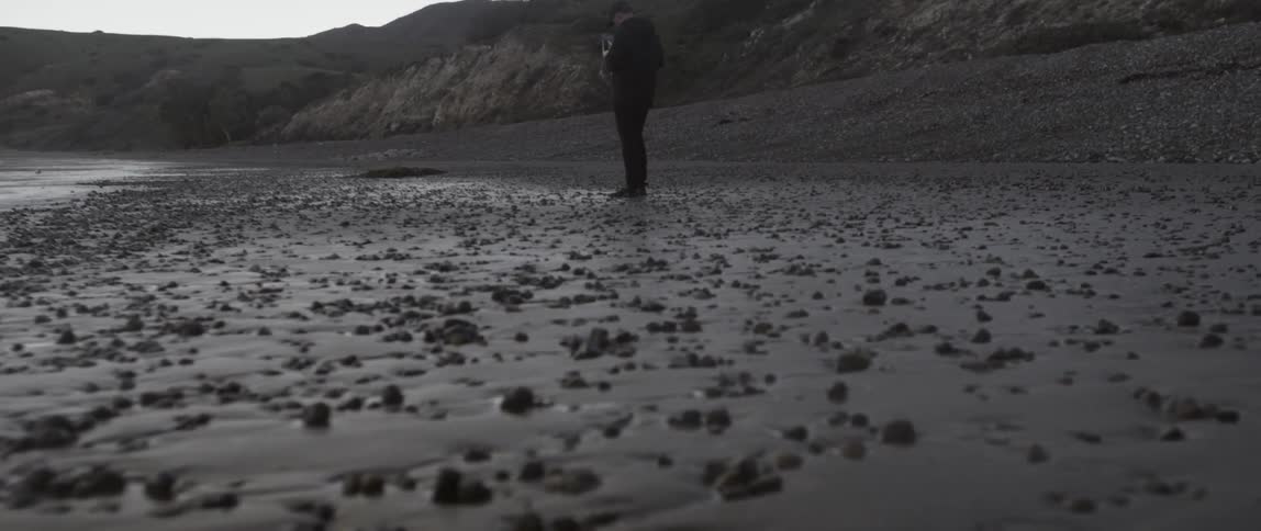 A man is standing on a rocky beach