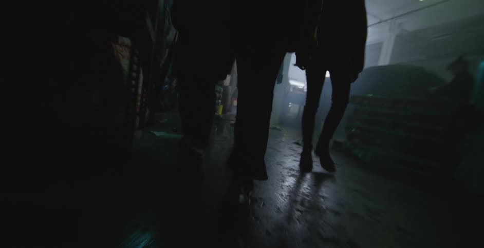 A group of people walk through a building littered with trash and debris