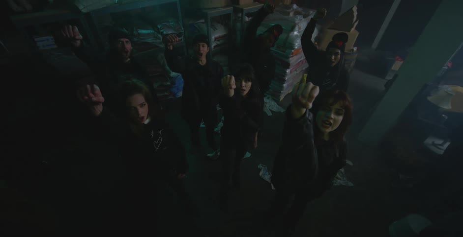 Group of people yell and protest while standing in dimly lit warehouse