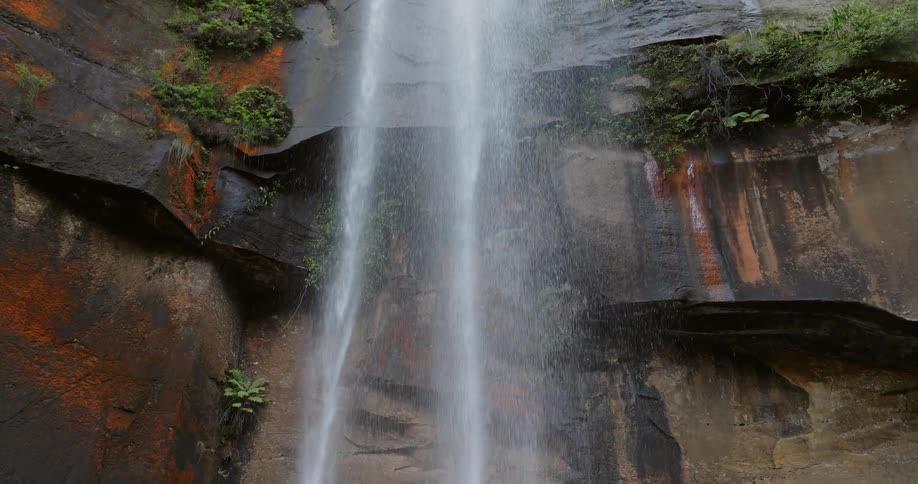 A rocky mountain waterfall with plants around it