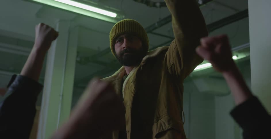 A bearded man raises his fist in the air and shouts while rallying others