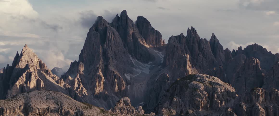 Heavy clouds cast shadows onto jagged mountains