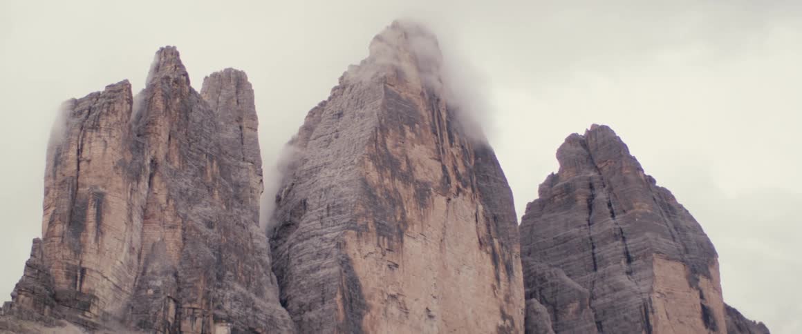 Three rocky peaks next to each other in a region with a lot of sand on a cloudy day