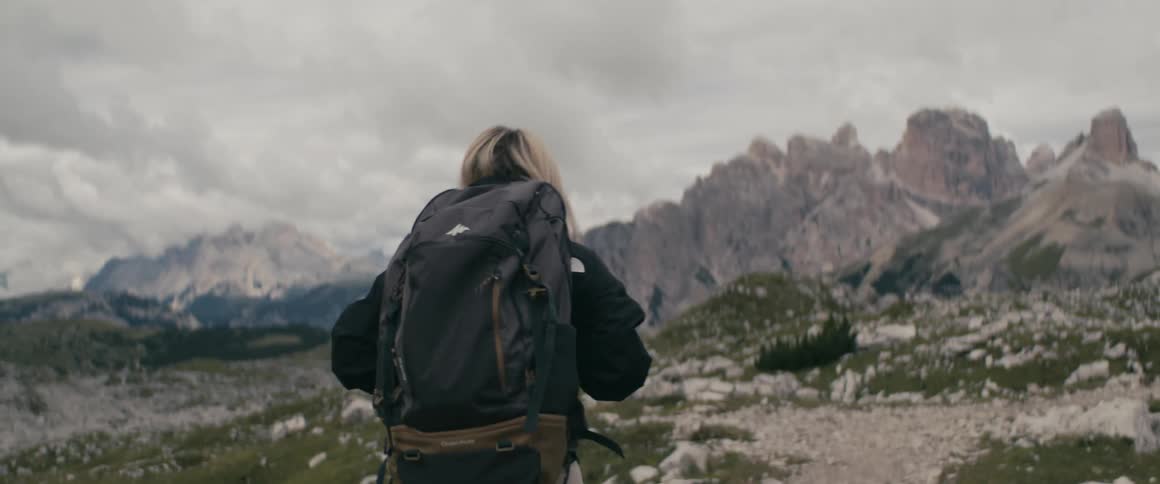 A woman hikes down a trail in the mountains