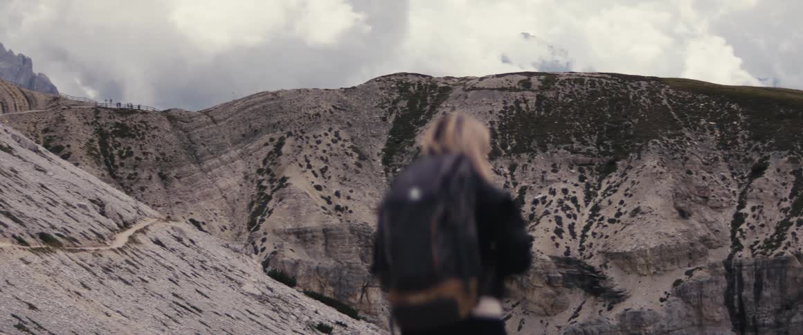 Backpacker stands onmountain ridge on cloudy day