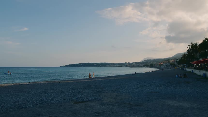 Landscape on a beach with people enjoying themselves and in the horizon a mountain range
