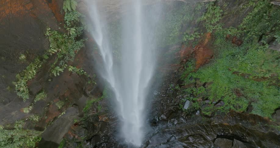 A waterfall flows down a tall cliff into a lake