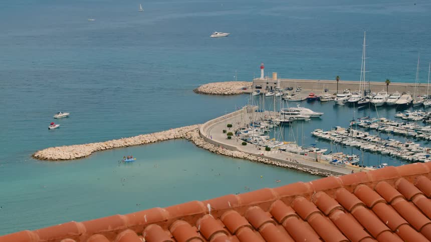 Port with several yachts docked and some moving on the sea