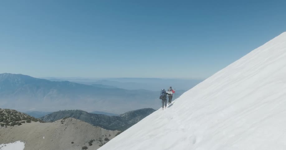Hikers climb on a snowy mountainside