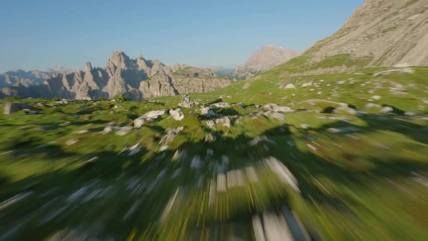 High energy FPV Drone camera flies swiftly over a rocky mountainous landscape on a sunny day