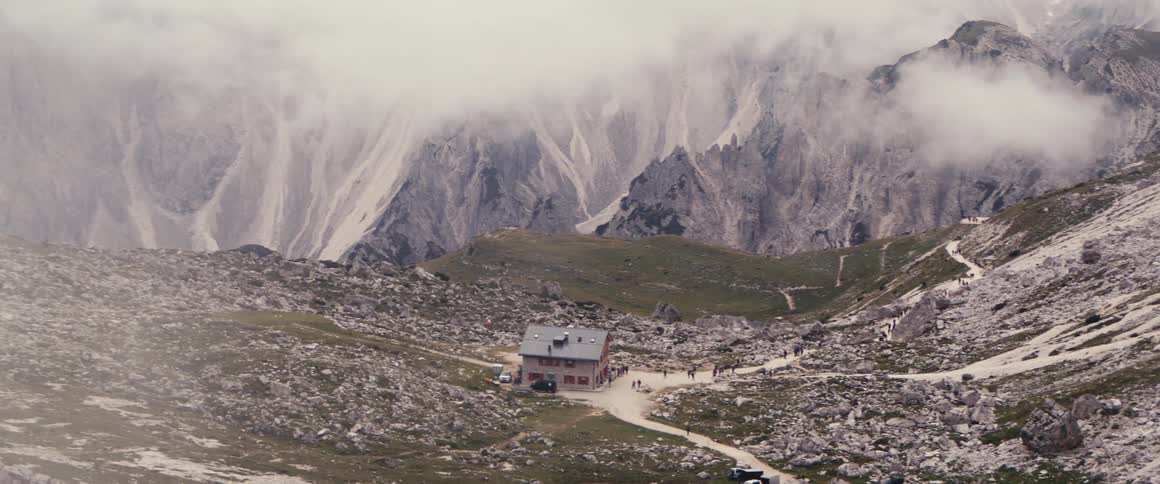 Shelter in the middle of the mountains and several people trekking under the mountains in winter