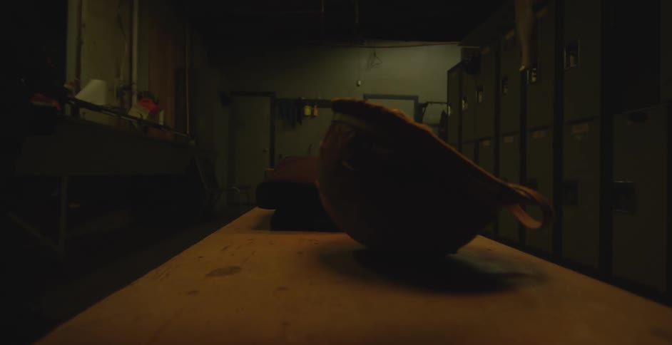 A person places a military helmet on a locker room bench