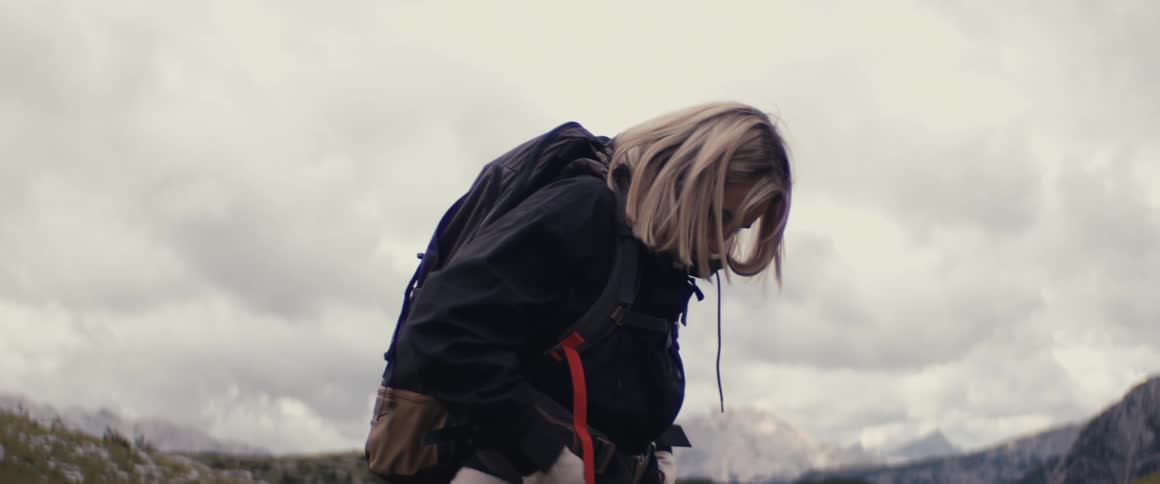 A woman hikes in a rocky mountain landscape on a cloudy day