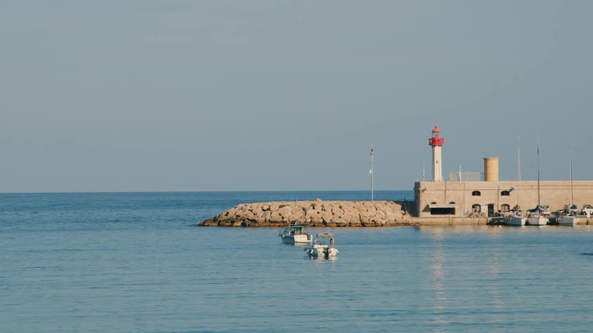 Boats sit near a peninsula with a lighthouse