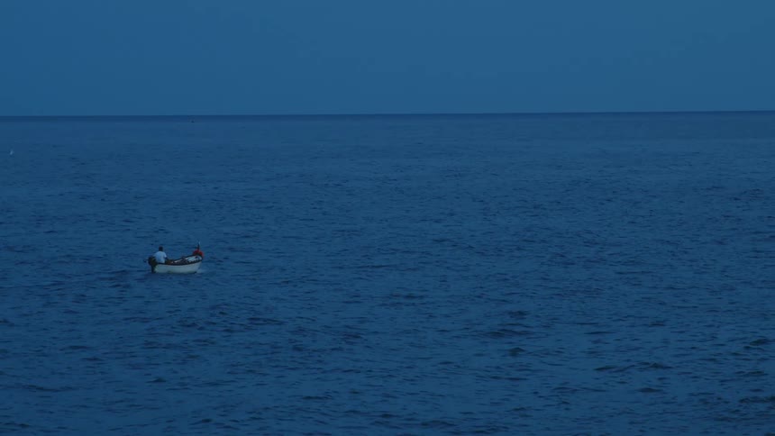 A boat sailing on the ocean watches the horizon at sunset